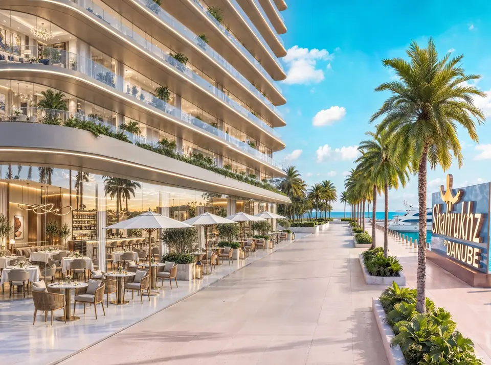 Waterfront promenade with outdoor dining under white parasols, palm trees and the sea